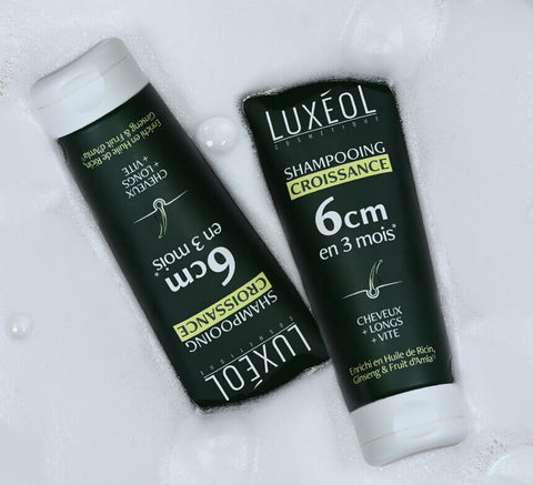 Two shampoo tubes on wet surface with water droplets.