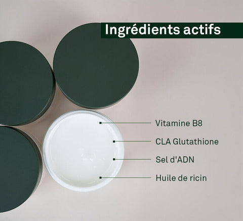 Overhead shot of open jar of white beauty product surrounded by closed green jars.
