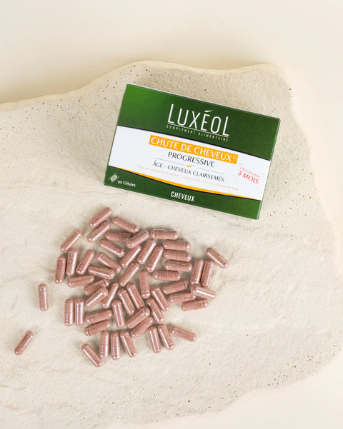 Luxéol hair color product packaging with pink capsules on a beige fabric background