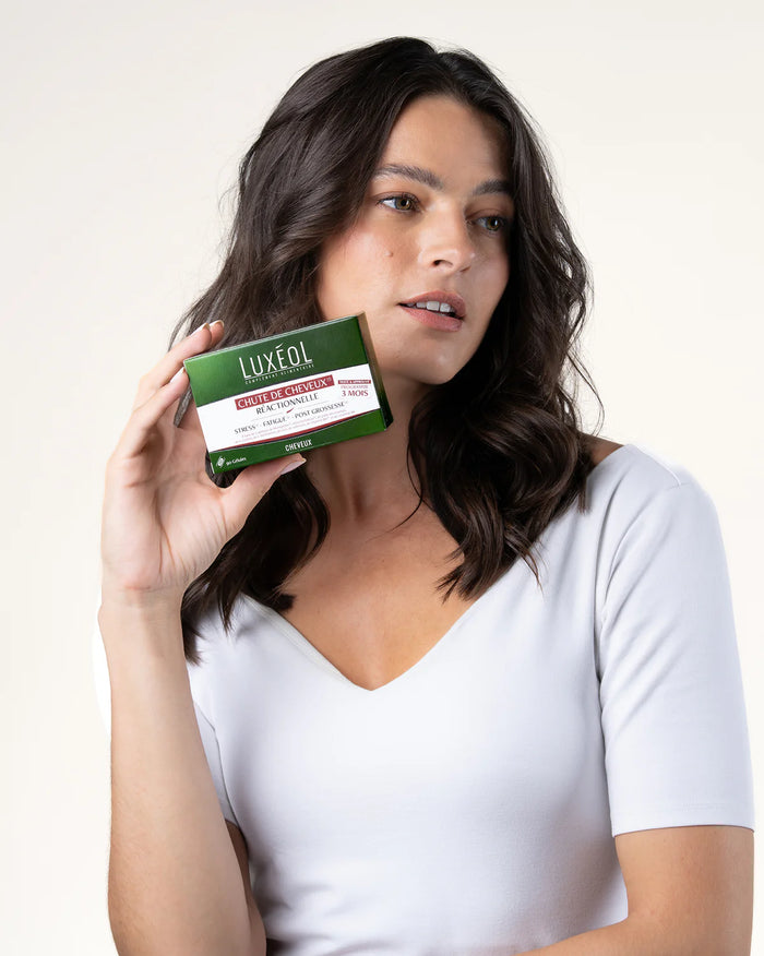 Woman holding a Luxeol product box against a white background