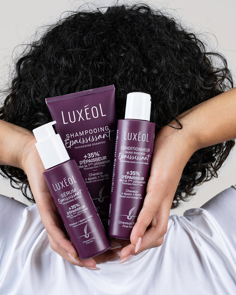 Person holding Luxéol hair care products with curly hair